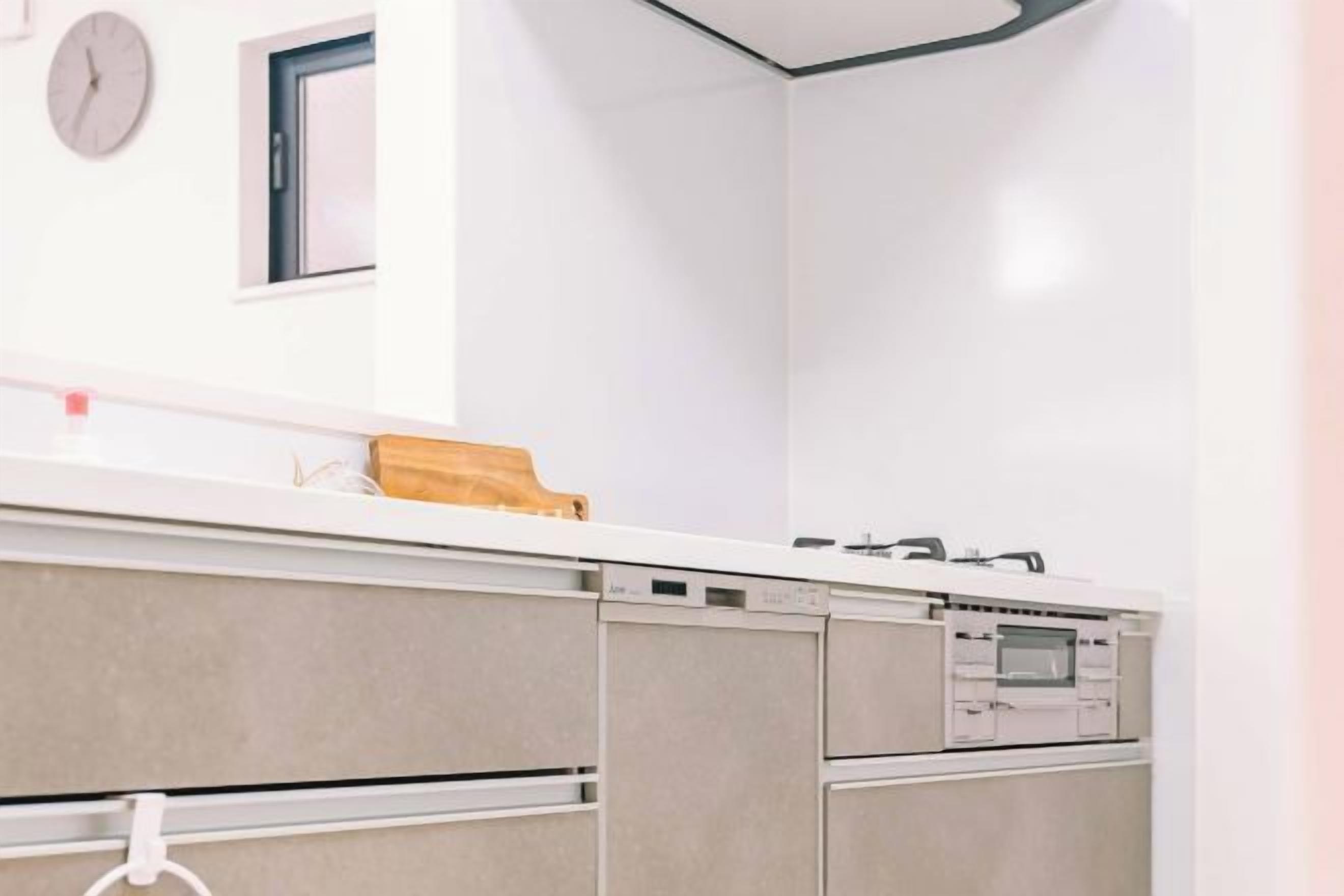 A modern kitchen with a white countertop, built-in oven, and a clock on the wall.