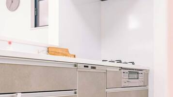 A modern kitchen with a white countertop, built-in oven, and a clock on the wall.