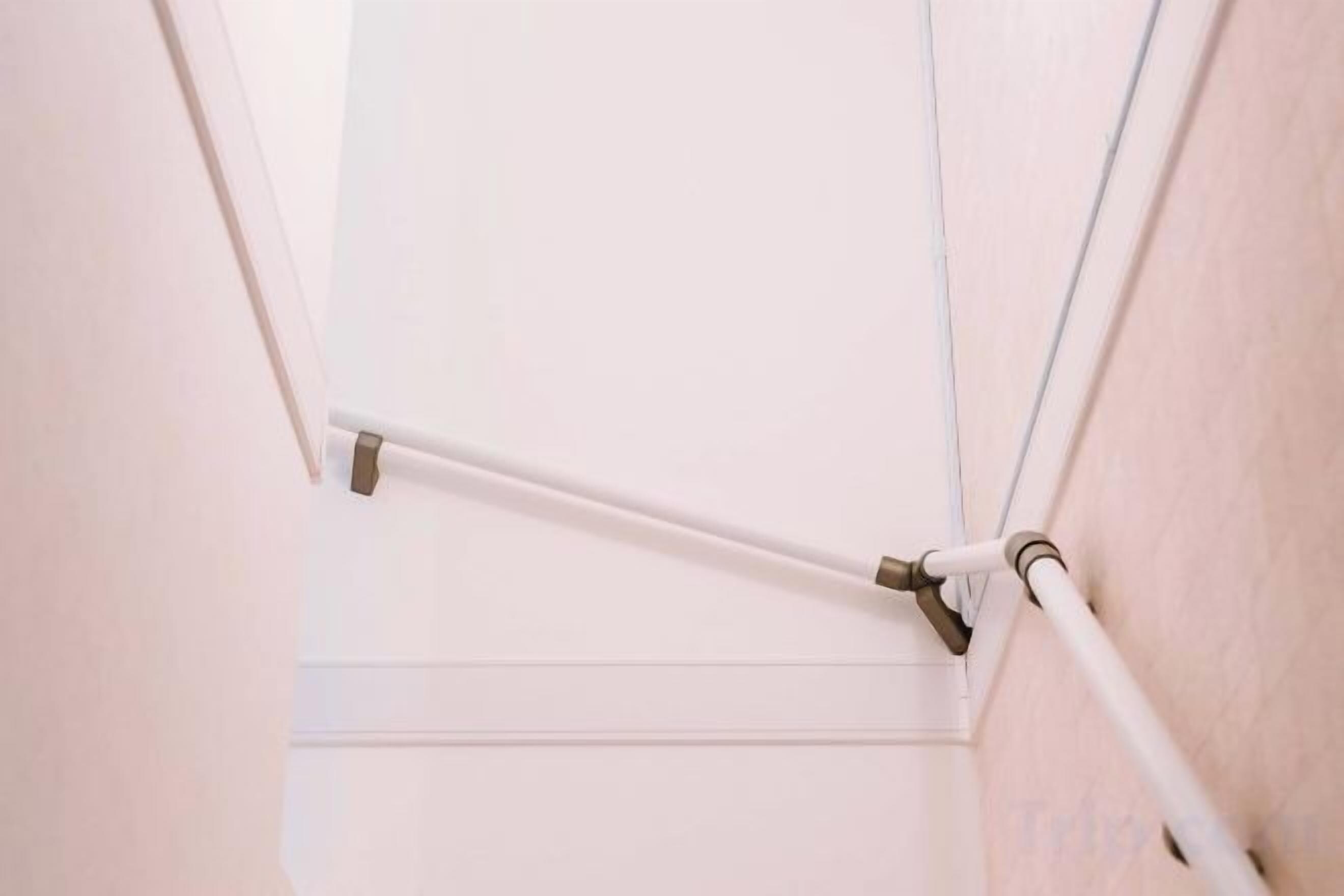 A corner of a room with a white pipe running along the wall and a white ceiling.
