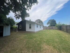 A single-story house with a black and white exterior, a fenced backyard, and a small shed. - Welcome to the Lion House, the house that welcomes you to Bentonville's downtown (Bentonville)