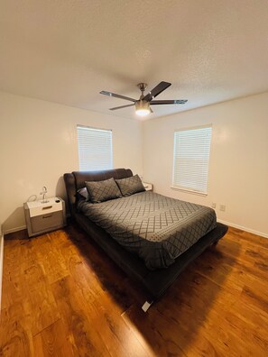 A bedroom with a bed, a nightstand, a ceiling fan, and two windows with blinds. - Welcome to the Lion House, the house that welcomes you to Bentonville's downtown (Bentonville)