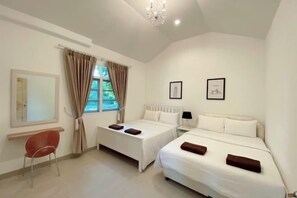 A hotel room with two beds, a red chair, a window with curtains, and framed pictures on the wall.