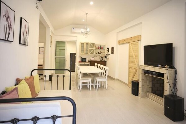 A living room with a sofa, a dining table with chairs, a fireplace, and a TV mounted on the wall. - Khaoyai Valley 9 (Pak Chong)