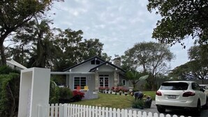 Een huis met een witte schutting, een oprit en een witte auto die ervoor geparkeerd staat.
