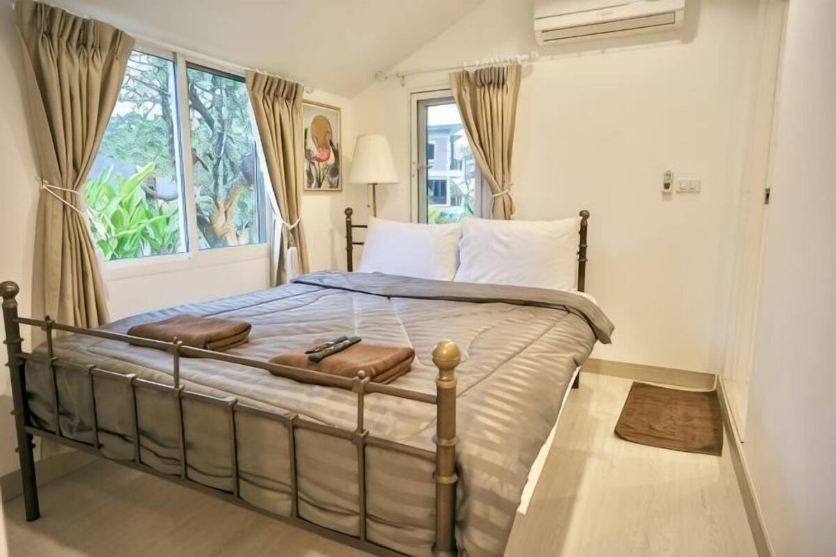 A bedroom with a bed, curtains, a lamp, and a window.