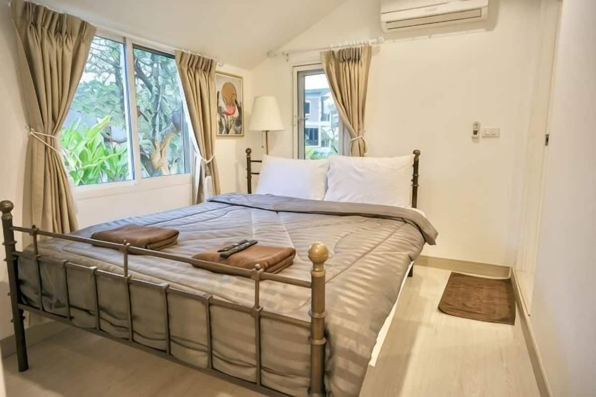 A bedroom with a bed, curtains, a lamp, and a window.