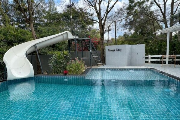 A swimming pool with a slide, a ladder, and a covered area.