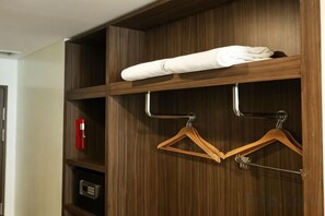 A wooden wardrobe with a folded white towel on top, a red object on the left shelf, and two wooden hangers on the right. - MCollection - Private Rooms in Historic Manila Chinatown (Manila)