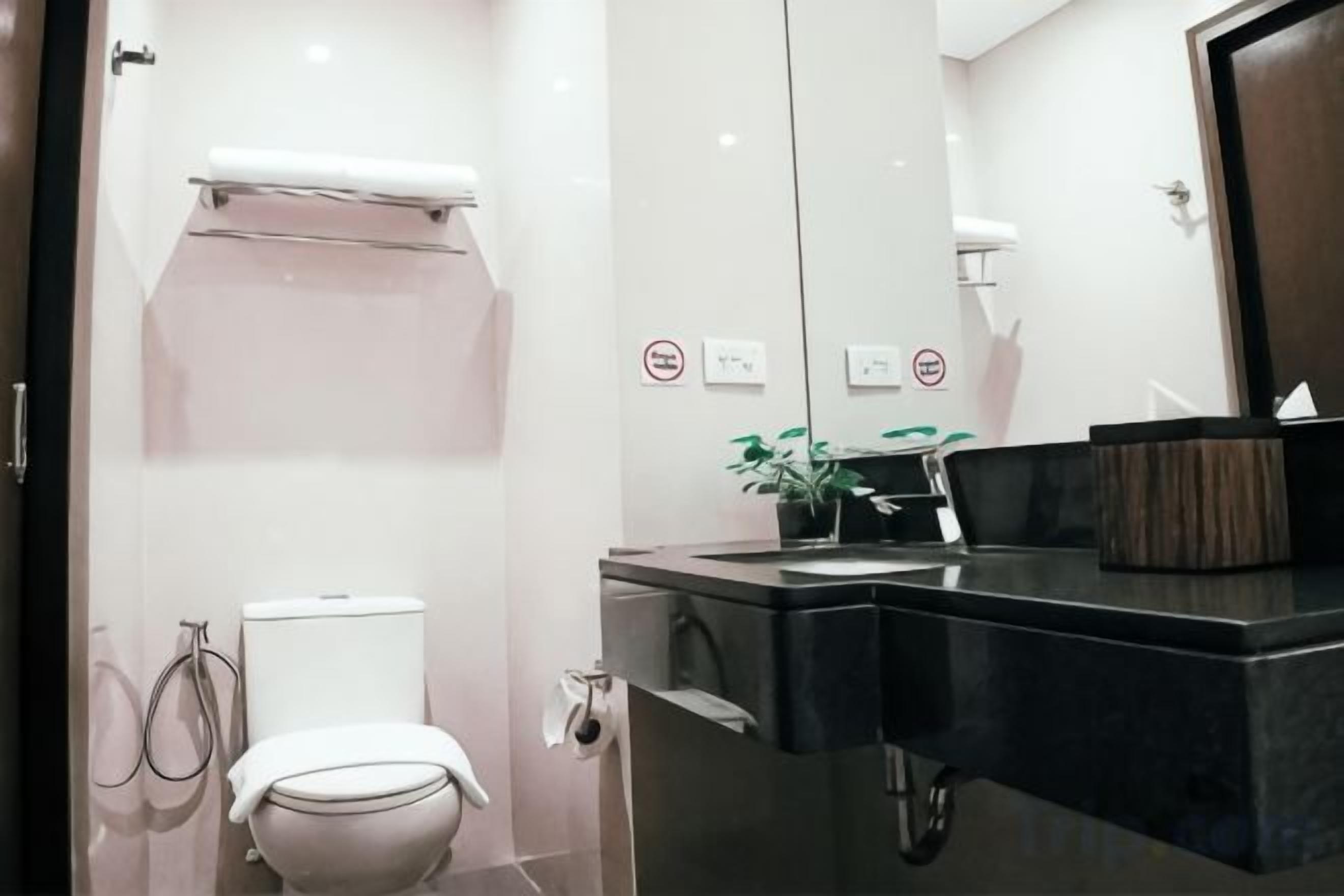 Une salle de bain moderne équipée de toilettes, d’un bidet et d’un lavabo avec un miroir.