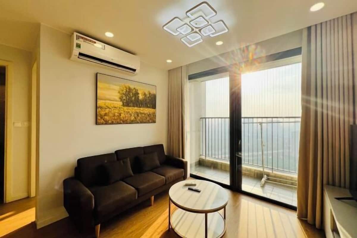 A modern living room with a sofa, a round coffee table, and a large window with a view of a balcony.