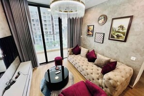 A modern living room with a tufted sofa, a round coffee table, and a chandelier.