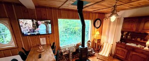 A wooden interior with a TV, a clock, a fireplace, and a dining area.