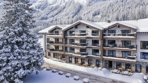 A multi-story hotel with balconies, outdoor seating, and a snowy mountain backdrop. - Bergresort Berwanger Hof by ALPS RESORTS (Berwang)