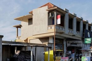 A multi-story building with a flat roof, large windows, and a visible flag. - Soka Asri Guest House near Bali Zoo RedPartner (Bali)