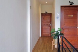 A hallway with wooden doors, a potted plant, and a sign indicating a staff-only area. - Red Panda Hostel & Cafe (Chiang Mai)