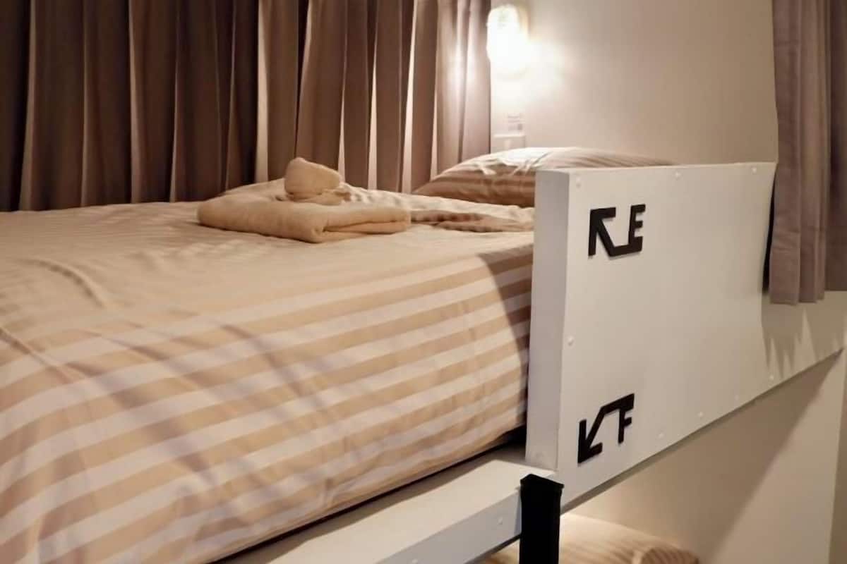 A bed with striped bedding, a pillow, and a headboard with a logo.