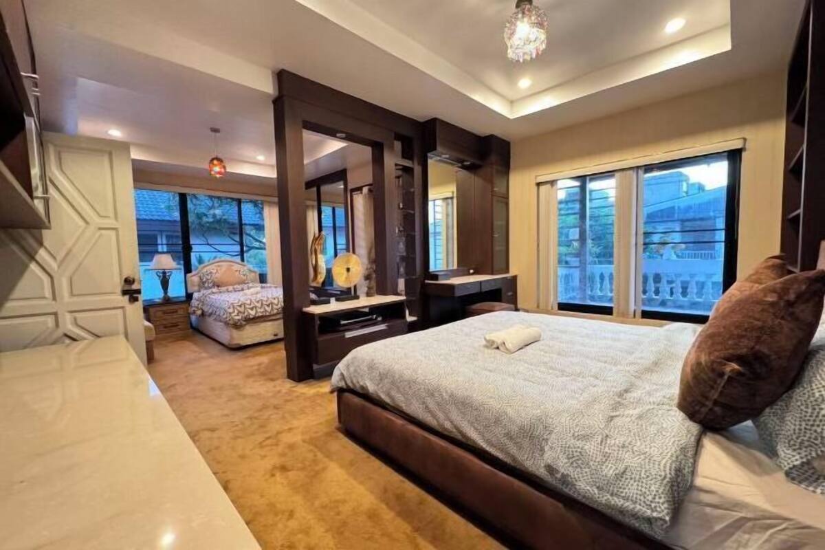 Ein Schlafzimmer mit einem großen Bett, einem Schreibtisch, einem Stuhl und einem Fenster mit Blick.