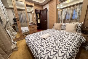 Een slaapkamer met een bed, een kledingkast, een spiegel en een raam.
