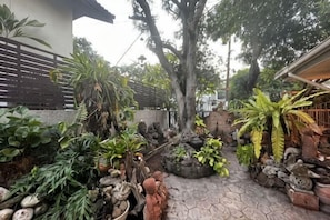 A garden with various plants, a stone pathway, and a fence.