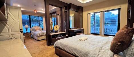A modern bedroom with a large bed, a sitting area, and a view of the outdoors.