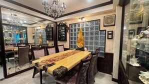 Un espace repas comprenant une longue table, des chaises, un lustre et une vitrine en verre contenant des objets décoratifs.