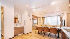 Une cuisine moderne avec des meubles en bois, un coin repas comprenant une table et des chaises, et une grande fenêtre avec des rideaux.