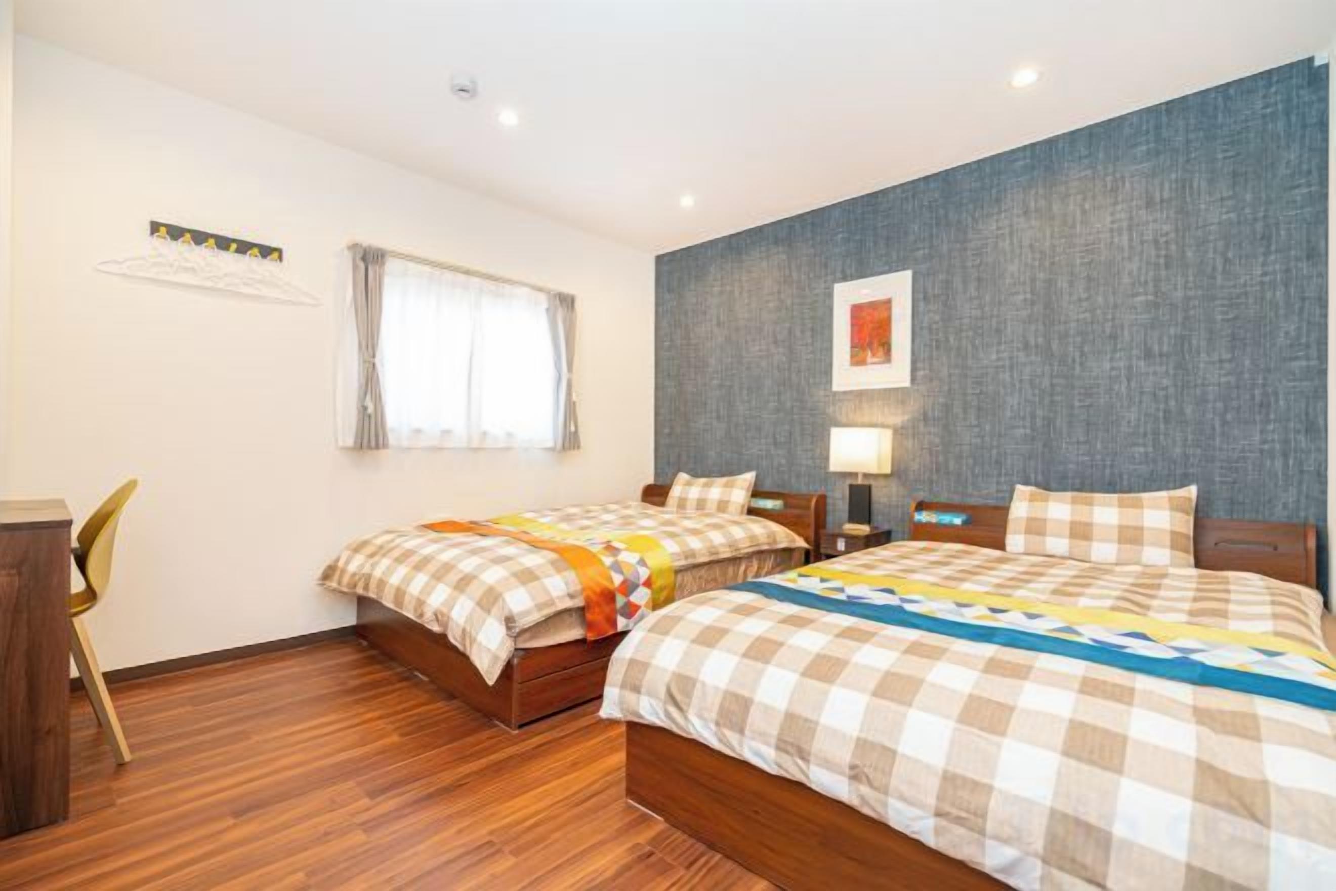 A hotel room with two beds, a desk, and a chair.
