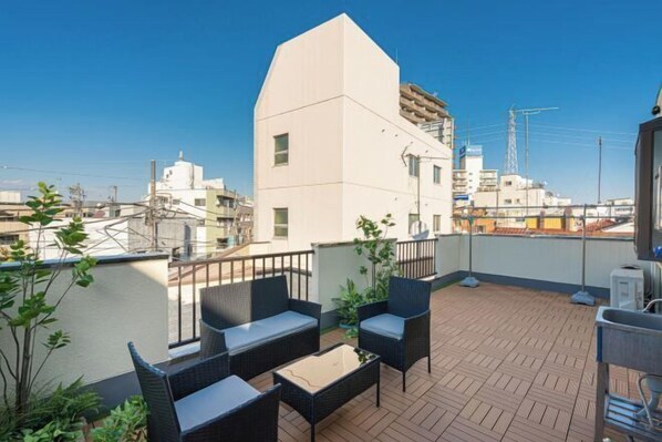 Une terrasse sur le toit, aménagée avec du mobilier d’extérieur, offrant une vue sur le paysage urbain et donnant sur un bâtiment doté d’une architecture originale.