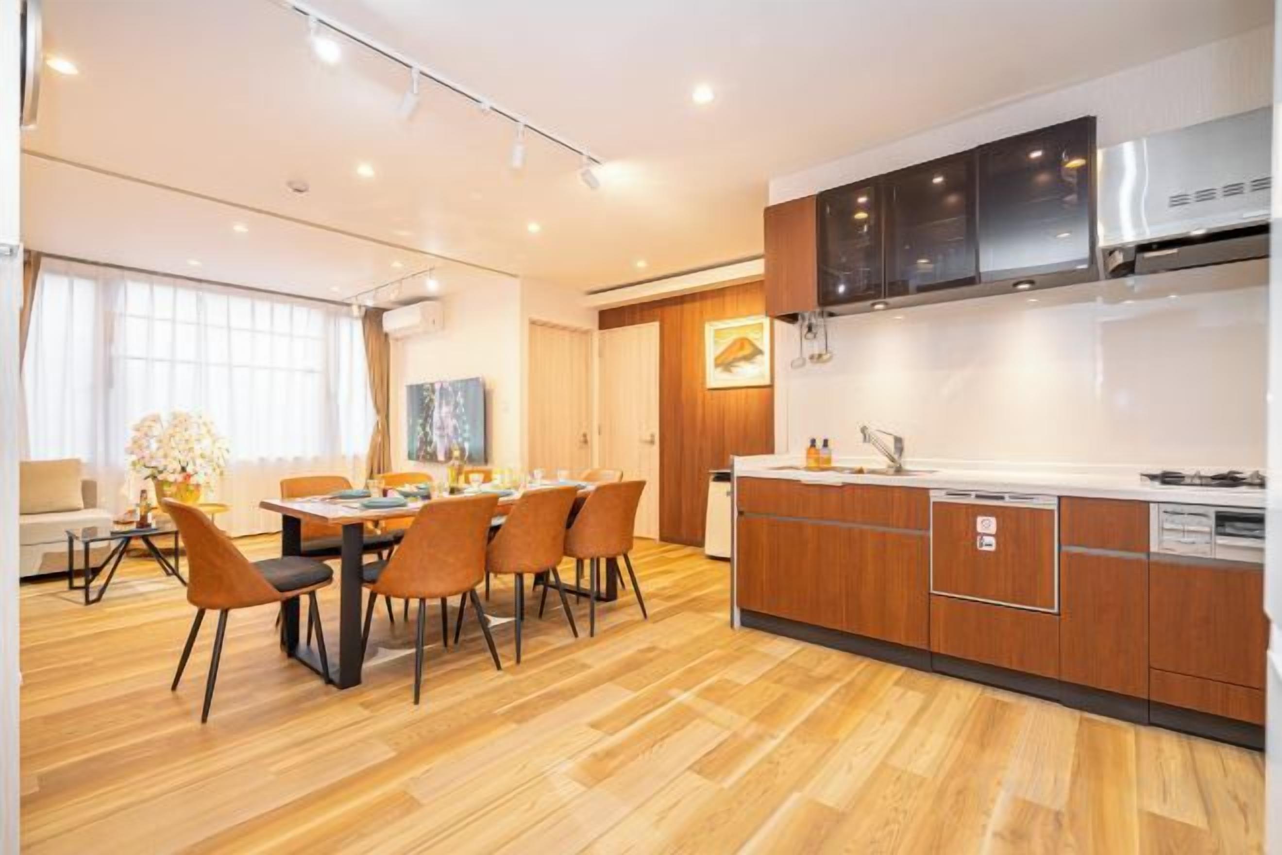 A modern kitchen with wooden cabinets, a dining area with a table and chairs, and a kitchen island with a sink.
