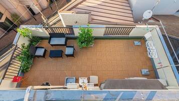 A rooftop terrace with outdoor seating, a barbecue area, and potted plants.
