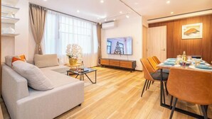 Un salon moderne comprenant un canapé, une table à manger et des chaises, un téléviseur et un meuble en bois.