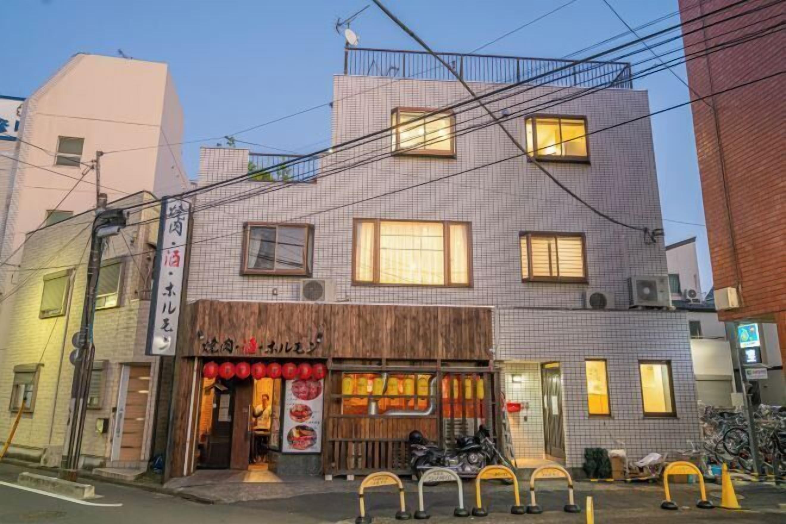 A two-story building with a restaurant on the ground floor, featuring a wooden facade and red lanterns.