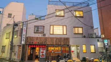 A two-story building with a restaurant on the ground floor, featuring a wooden facade and red lanterns.