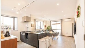 Une cuisine moderne dotée d’un îlot central, d’un coin repas avec des chaises et d’une grande fenêtre qui laisse entrer la lumière naturelle.