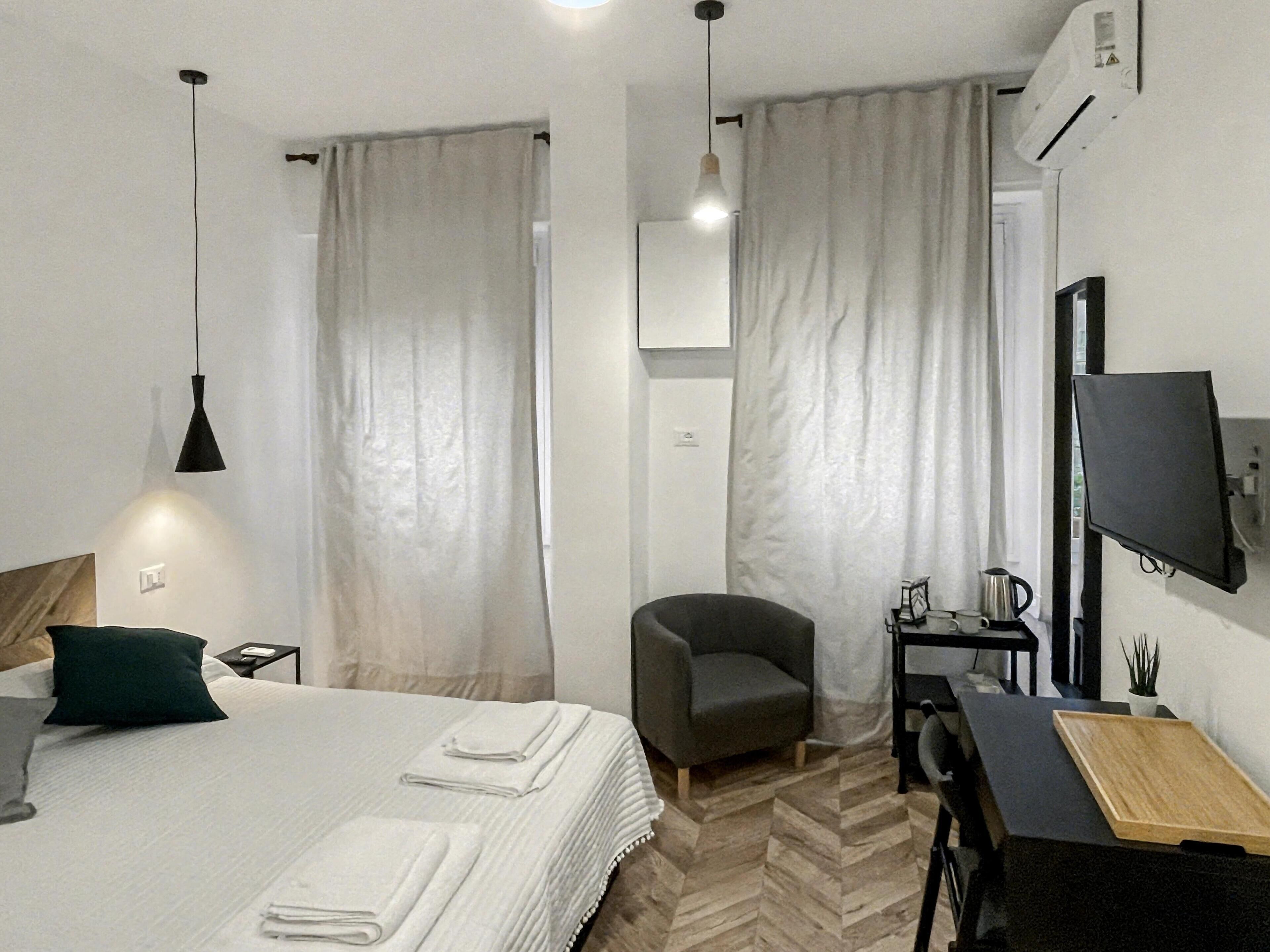 A hotel room with a bed, a desk, a chair, a TV, and a coffee maker.