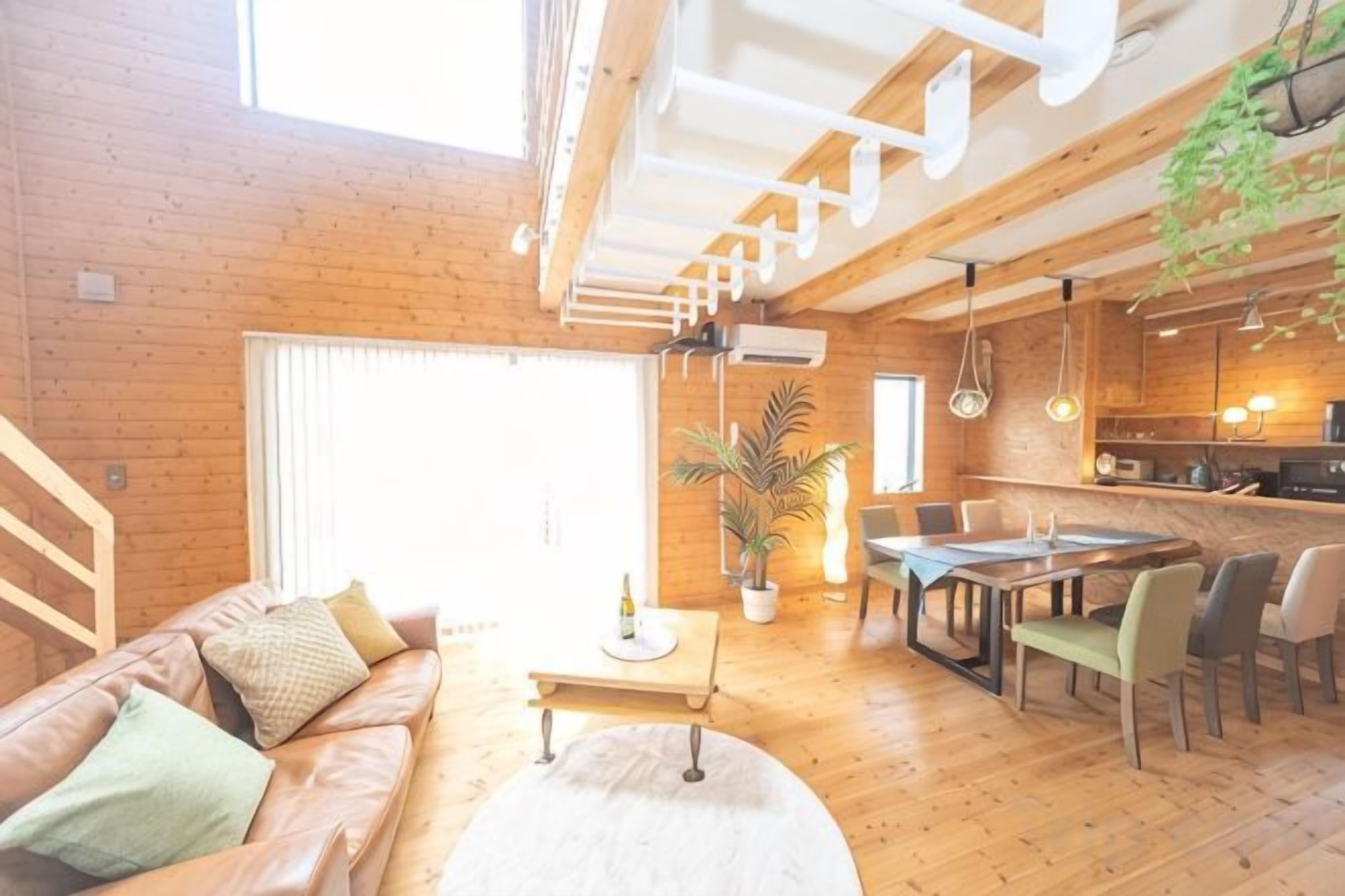 Un intérieur en bois comprenant un canapé, une table à manger, des chaises et un escalier.