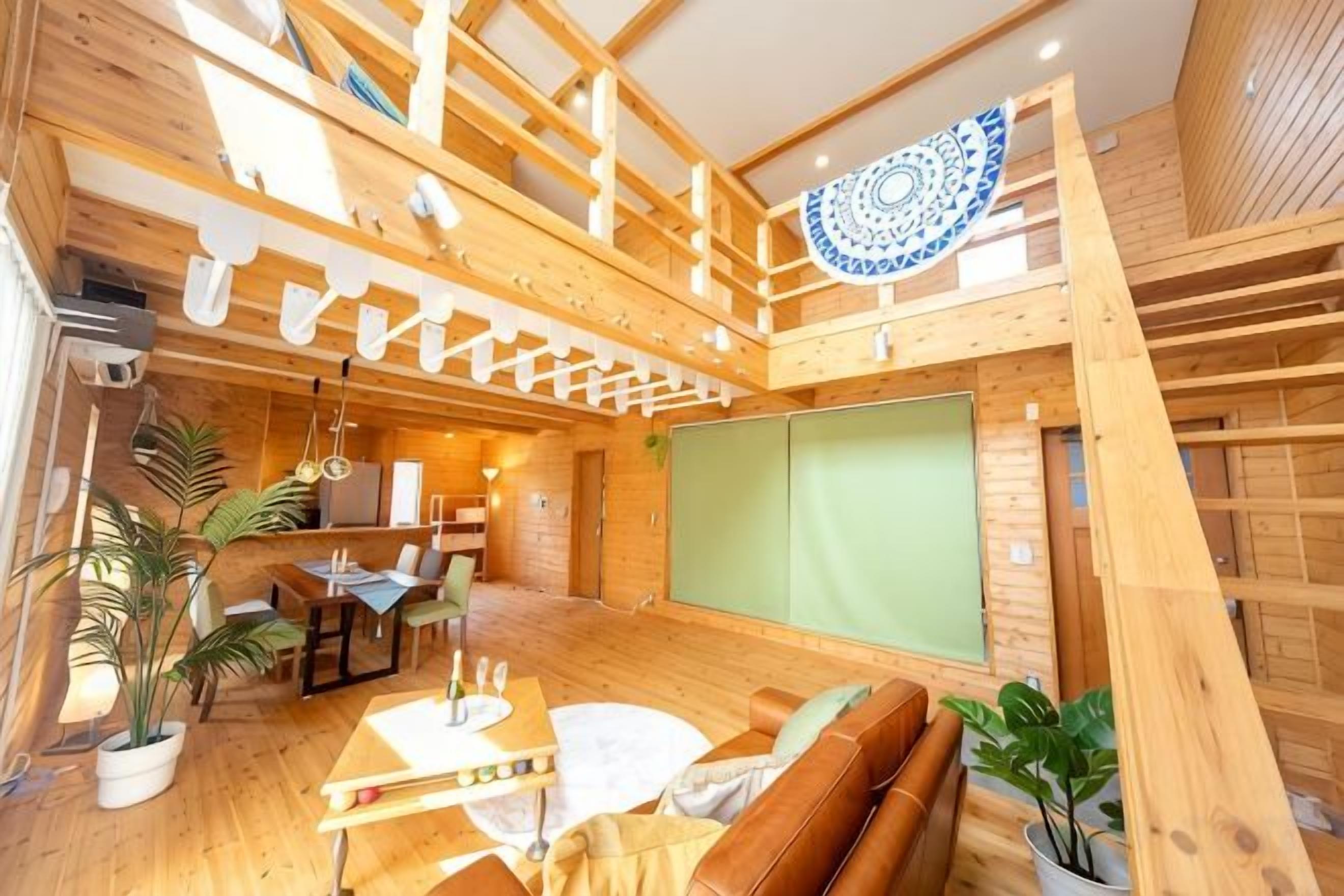 Un intérieur en bois comprenant un coin repas, un canapé et un grand écran vert.