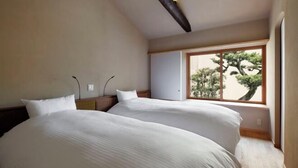 A bedroom with two beds, a window with a view of trees, and a wooden ceiling beam. - Kyo No Ondokoro Kamanza Nijo #2 (Kyoto)