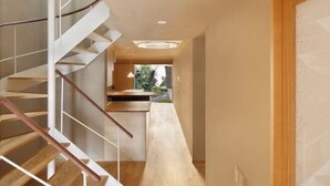 A modern interior with a spiral staircase, a long hallway, and a view of a garden. - Kyo No Ondokoro Kamanza Nijo #2 (Kyoto)