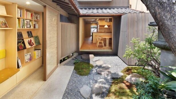A modern interior with a wooden bookshelf, a dining area, and a small garden with rocks and moss. - Kyo No Ondokoro Kamanza Nijo #2 (Kyoto)