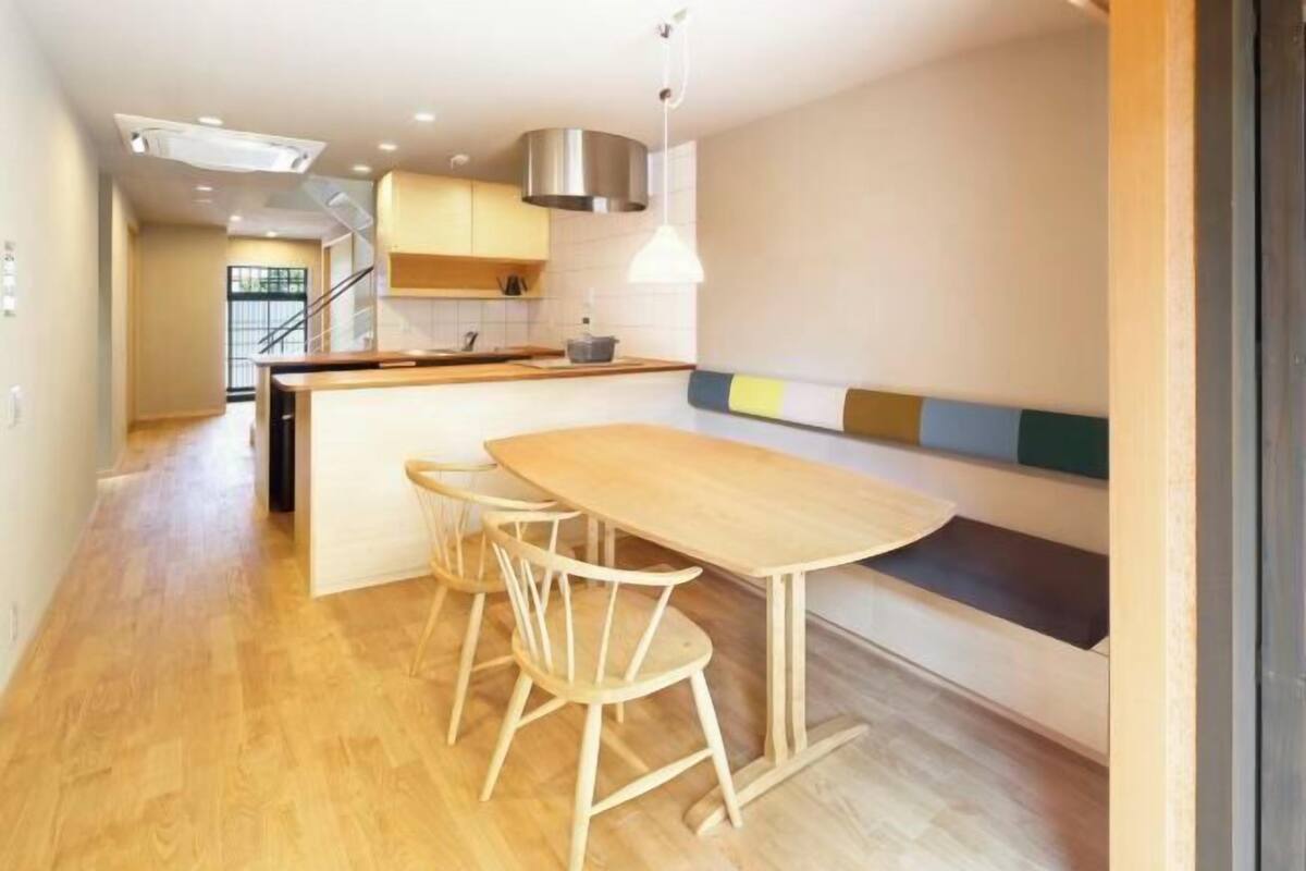 Une cuisine moderne avec un plancher en bois, un îlot central doté de tabourets et un banc intégré.