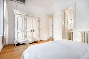 Camera da letto con un letto grande, un armadio bianco e una porta che dà su un'altra stanza.