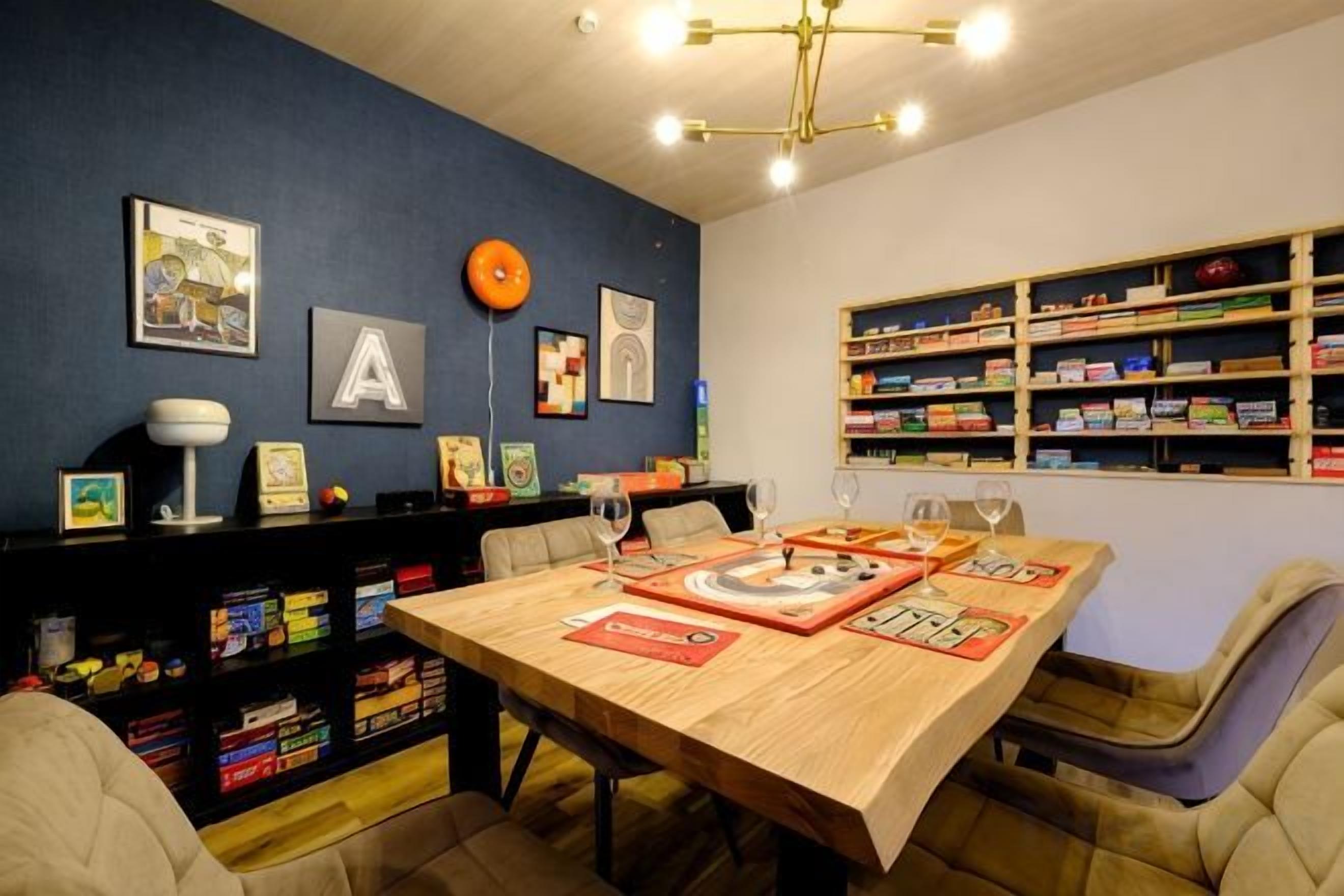 A dining area with a wooden table, chairs, and a bookshelf filled with books and decorative items.