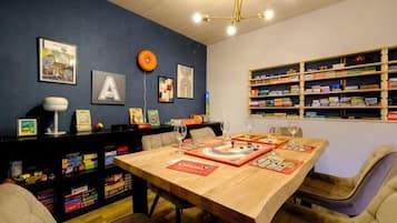 A dining area with a wooden table, chairs, and a bookshelf filled with books and decorative items.