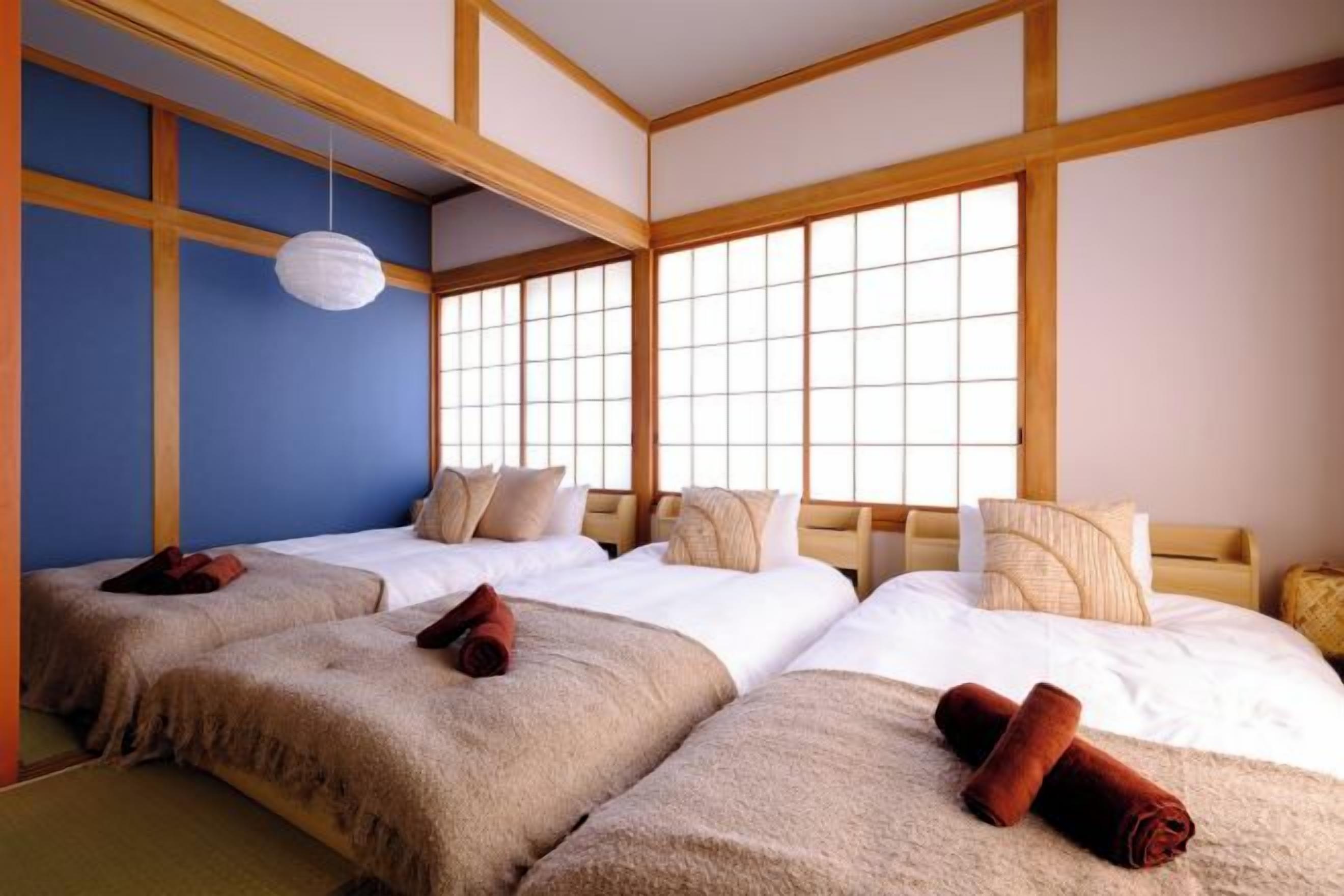 A traditional Japanese-style room with tatami flooring, a shoji screen, and a wooden ceiling.