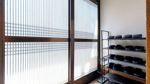 A room with a sliding door, a tiled floor, and a wall-mounted shoe rack with multiple shelves. - Board Game House Tokyo (Tokyo)