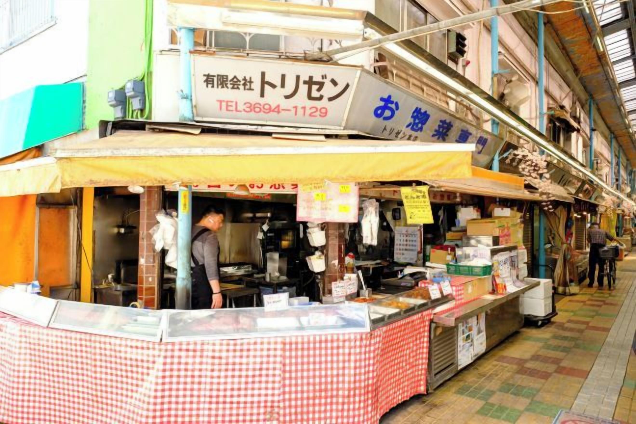 A food stall with a checkered tablecloth, a signboard, and a person behind the counter.
