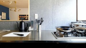 A modern kitchen with a gas stove, a coffee maker, and a knife on a cutting board. - Board Game House Tokyo (Tokyo)