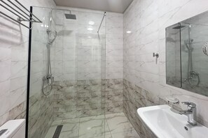 A bathroom with a glass-enclosed shower, a sink, and a mirror. - Reikartz Qarshi (Beshkent)