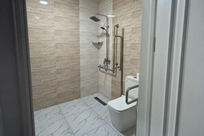 A modern bathroom with a shower, toilet, and a glass door.